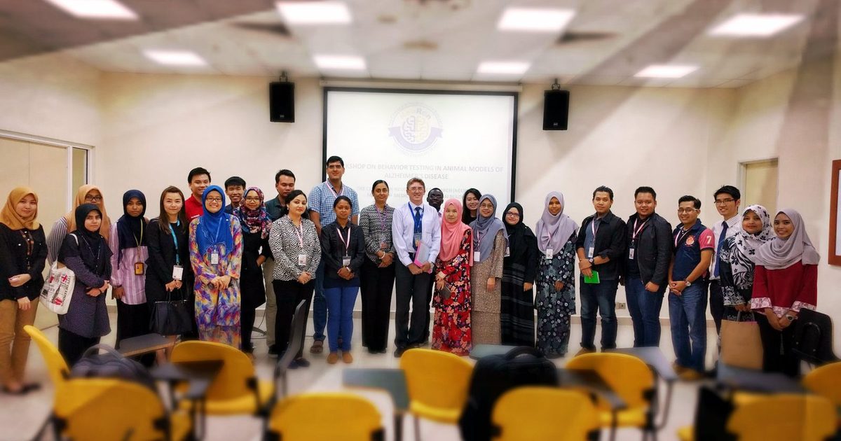 A large group of participants and organisers standing together for a group photo in a seminar room