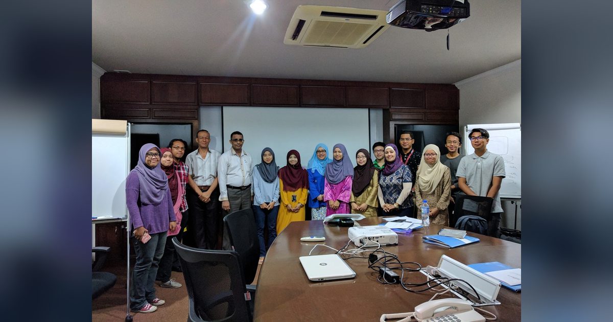The workshop group standing together for a photo in a meeting room with a long table and a projector
