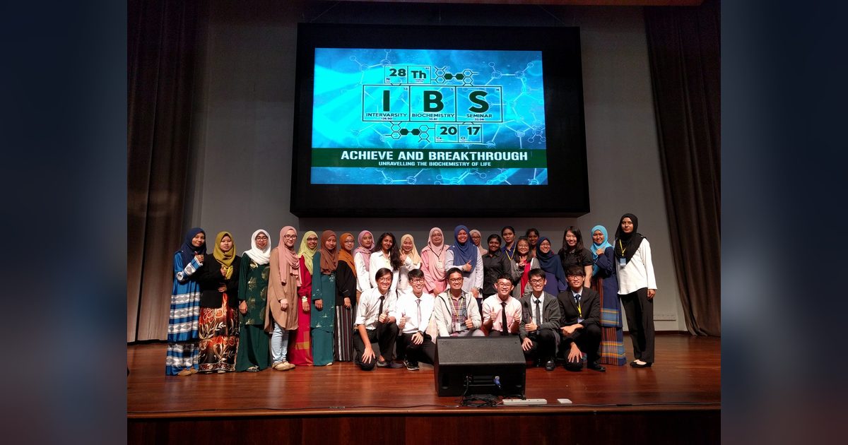 Participants pose for a group photo on stage under a large screen showing the IBS 2017 seminar logo