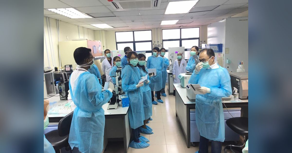 Workshop participants in blue gowns, masks and shoe covers in the tissue culture laboratory