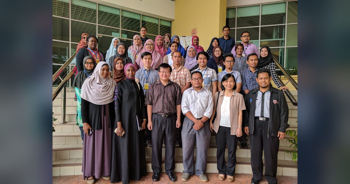 Workshop participants gathered for a group photo on an outdoor staircase at UPM