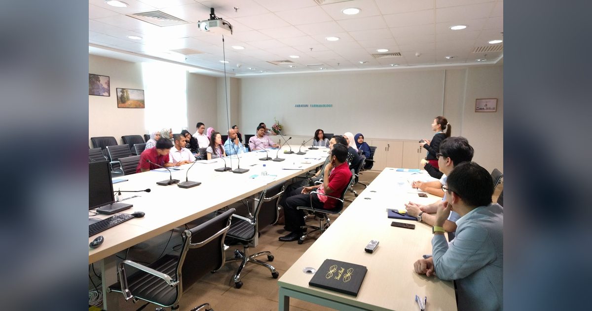 Researchers seated around long tables in the PPUKM seminar room, with a presenter standing at the front