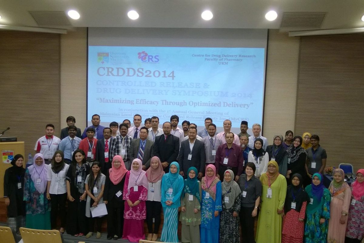 Delegates of CRDDS2014 pose for a group photo in a lecture hall, in front of the symposium title slide