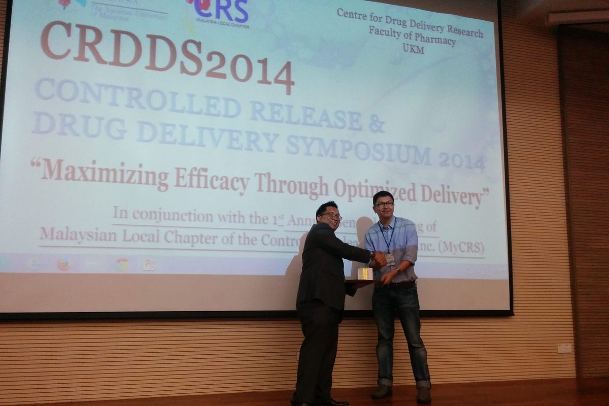 Two men shake hands on the stage in front of the CRDDS2014 title slide
