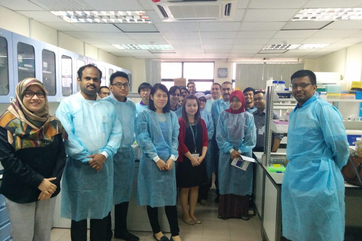 Workshop participants in blue laboratory gowns stand together in a laboratory at the Tissue Engineering Centre
