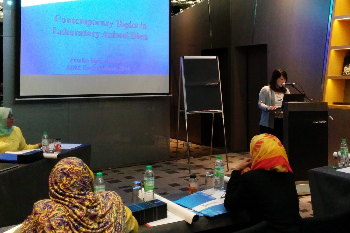 A speaker at the lectern beside a slide titled Contemporary Topics in Laboratory Animal Diets