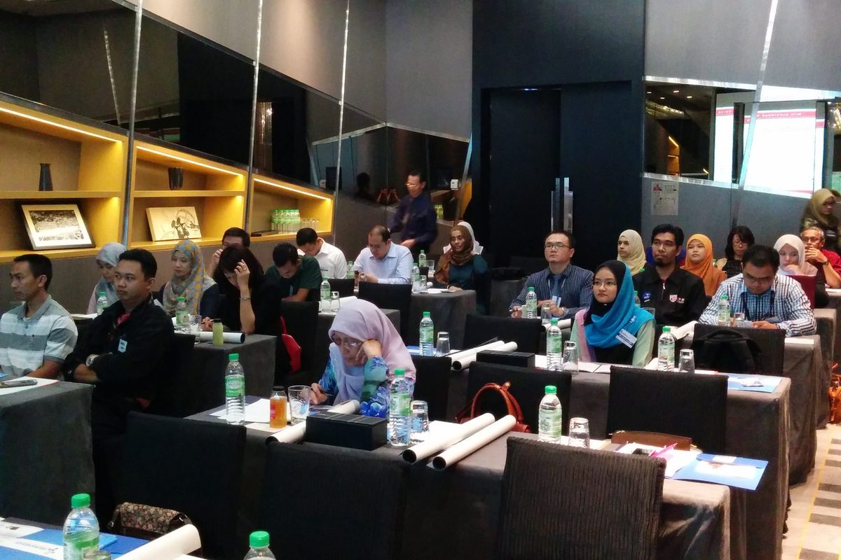Participants seated at rows of tables in the seminar room, facing the front