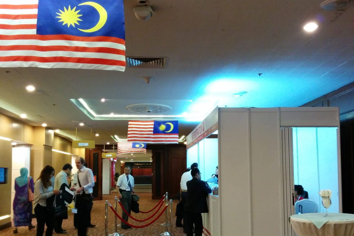 Delegates at the congress registration counter in a foyer hung with Malaysian flags
