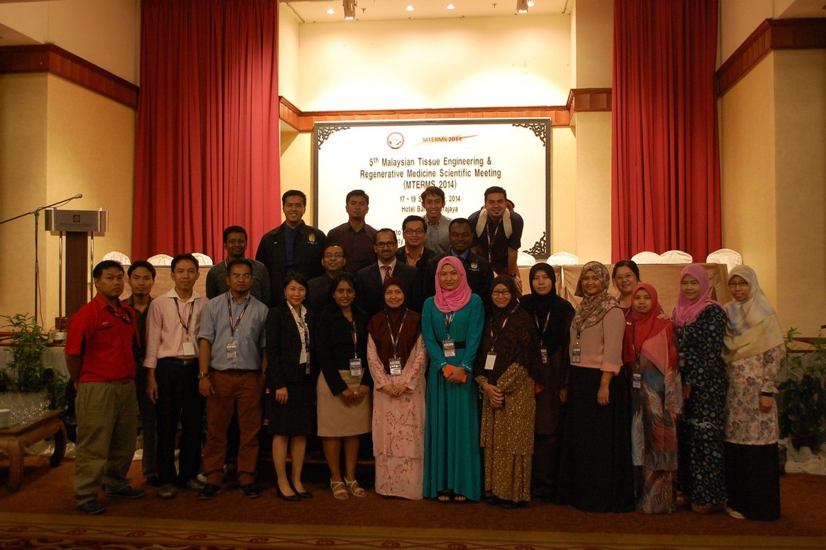 Delegates of MTERMS 2014 pose for a group photo in a hotel hall, in front of a board with the meeting name, dates and venue
