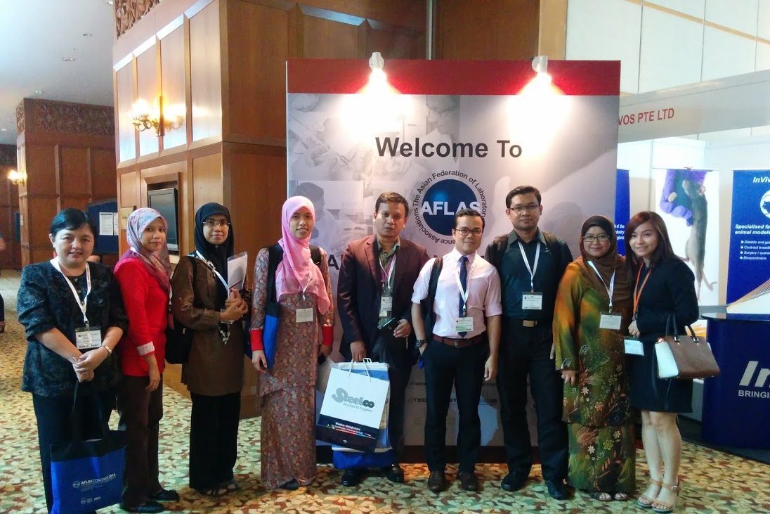 Nine delegates stand together in front of the Welcome to AFLAS board at the congress