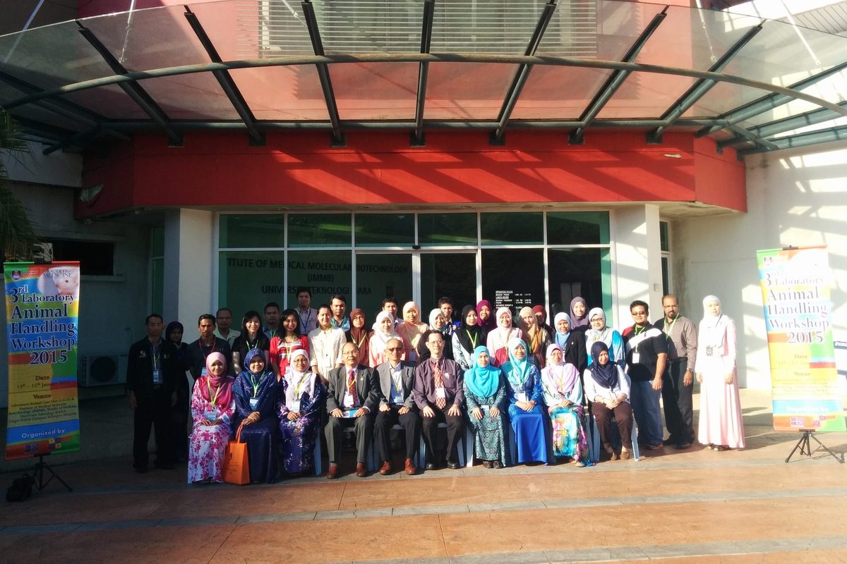 A large group of participants and organisers outside a building entrance, between two workshop banners