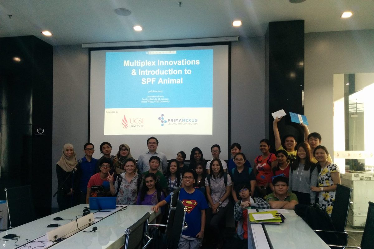 A large group of students and staff in a seminar room, in front of a screen showing the talk's title slide