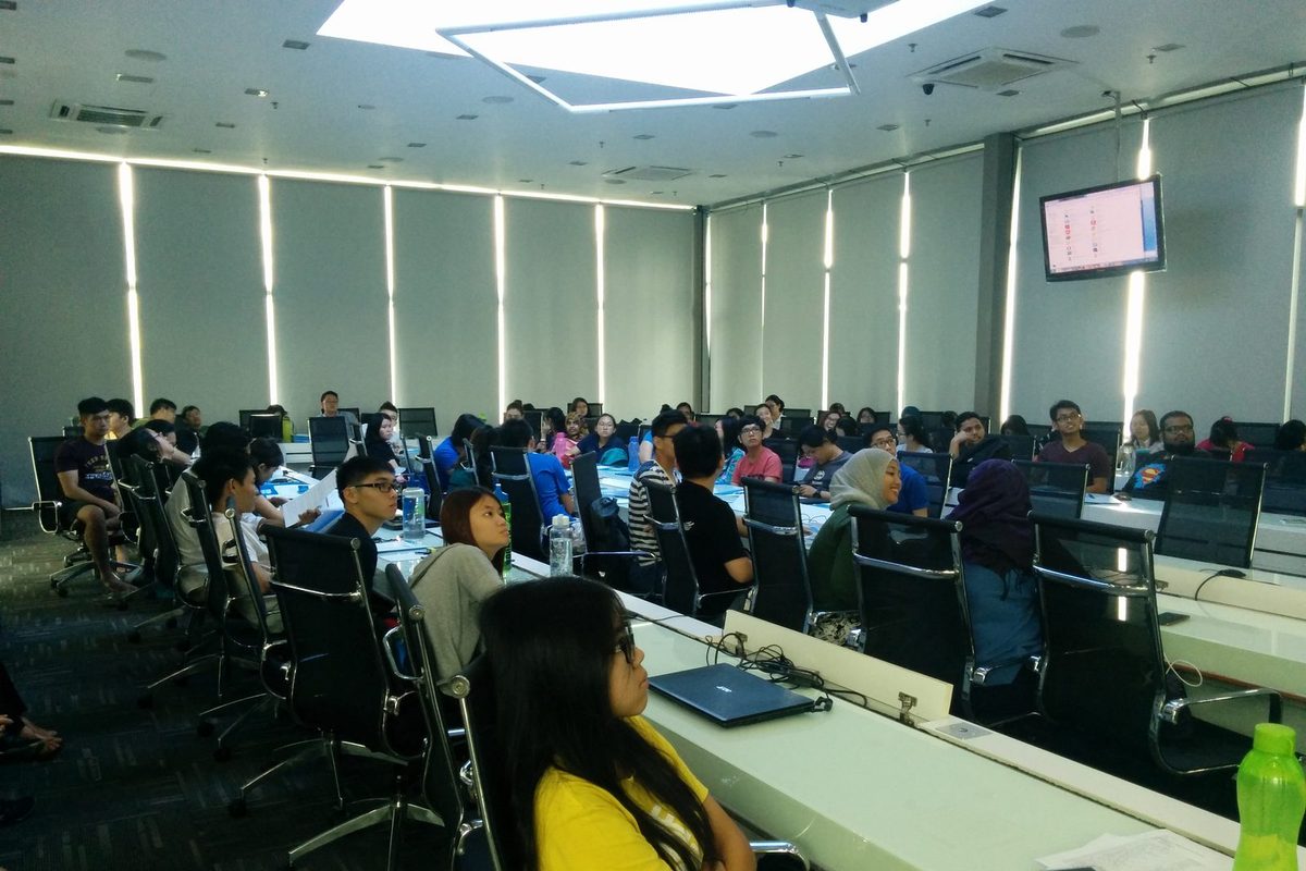 Students seated along rows of long tables in a seminar room