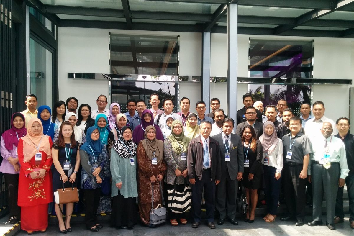 Group photo of the seminar participants standing in rows under a glass canopy at Le Meridien Kuala Lumpur