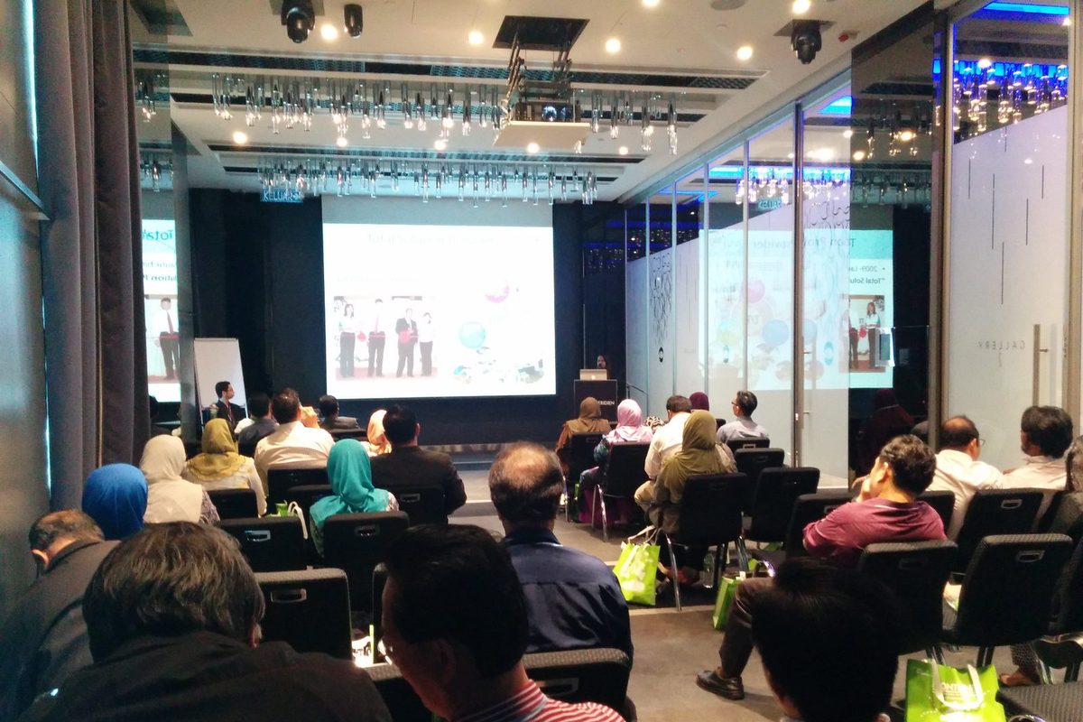 Seated audience in the hotel meeting room watching a talk on the projection screen