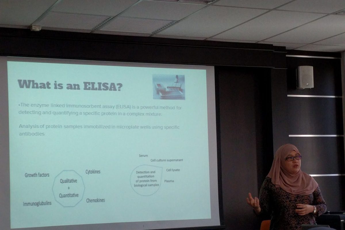 A trainer presents a slide titled What is an ELISA? to the seminar room