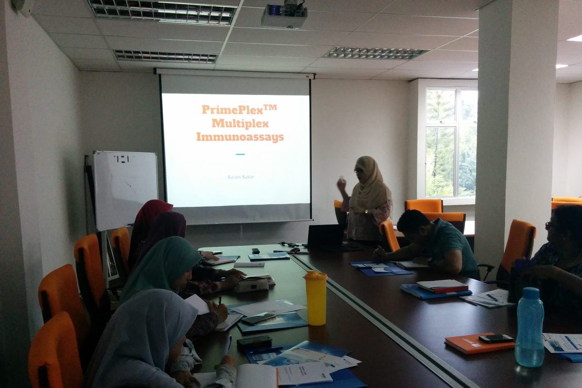 Participants seated at a meeting table during a talk on PrimePlex multiplex immunoassays