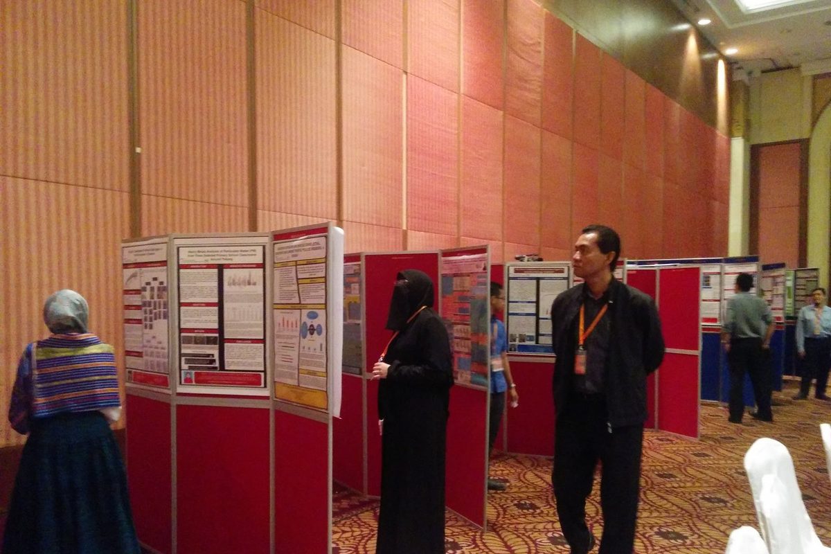 Delegates reading research posters mounted on red display boards in the conference hall