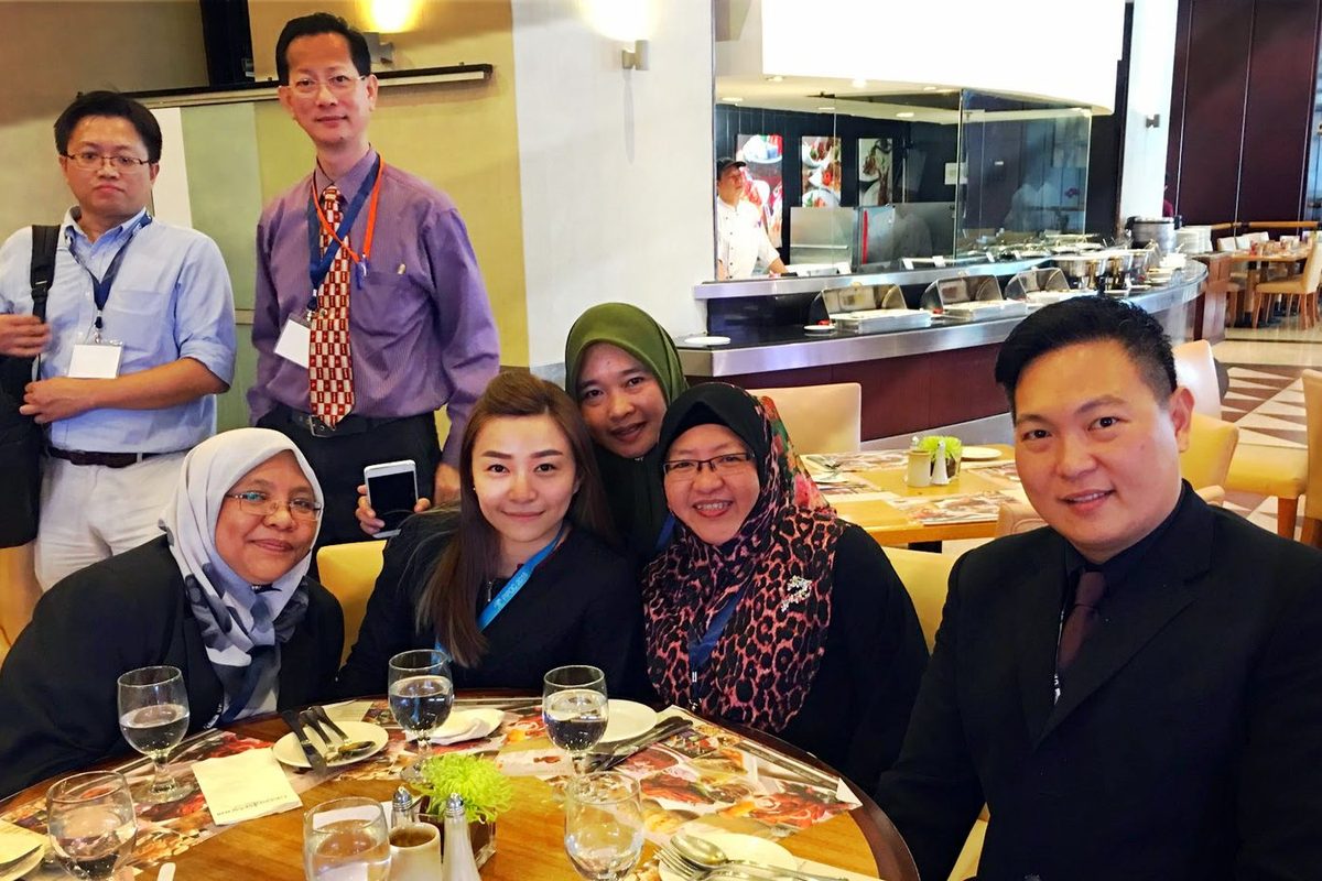 Conference delegates seated and standing around a lunch table at the hotel