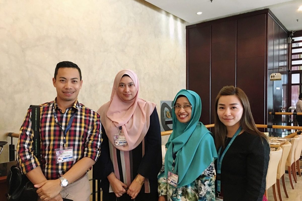 Four conference delegates wearing name badges stand together in the hotel