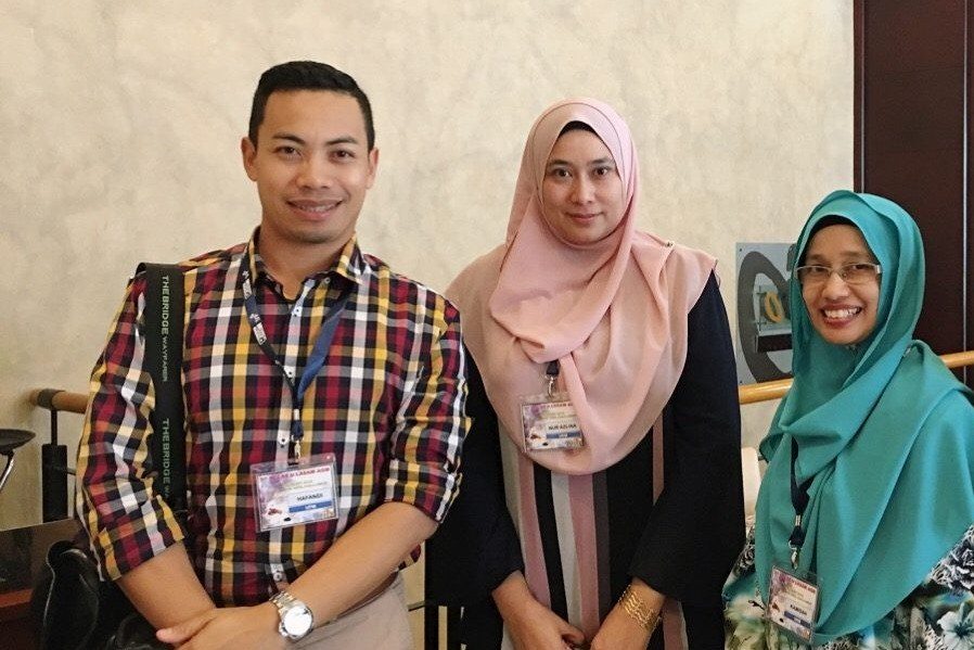 Three conference delegates stand together in the hotel