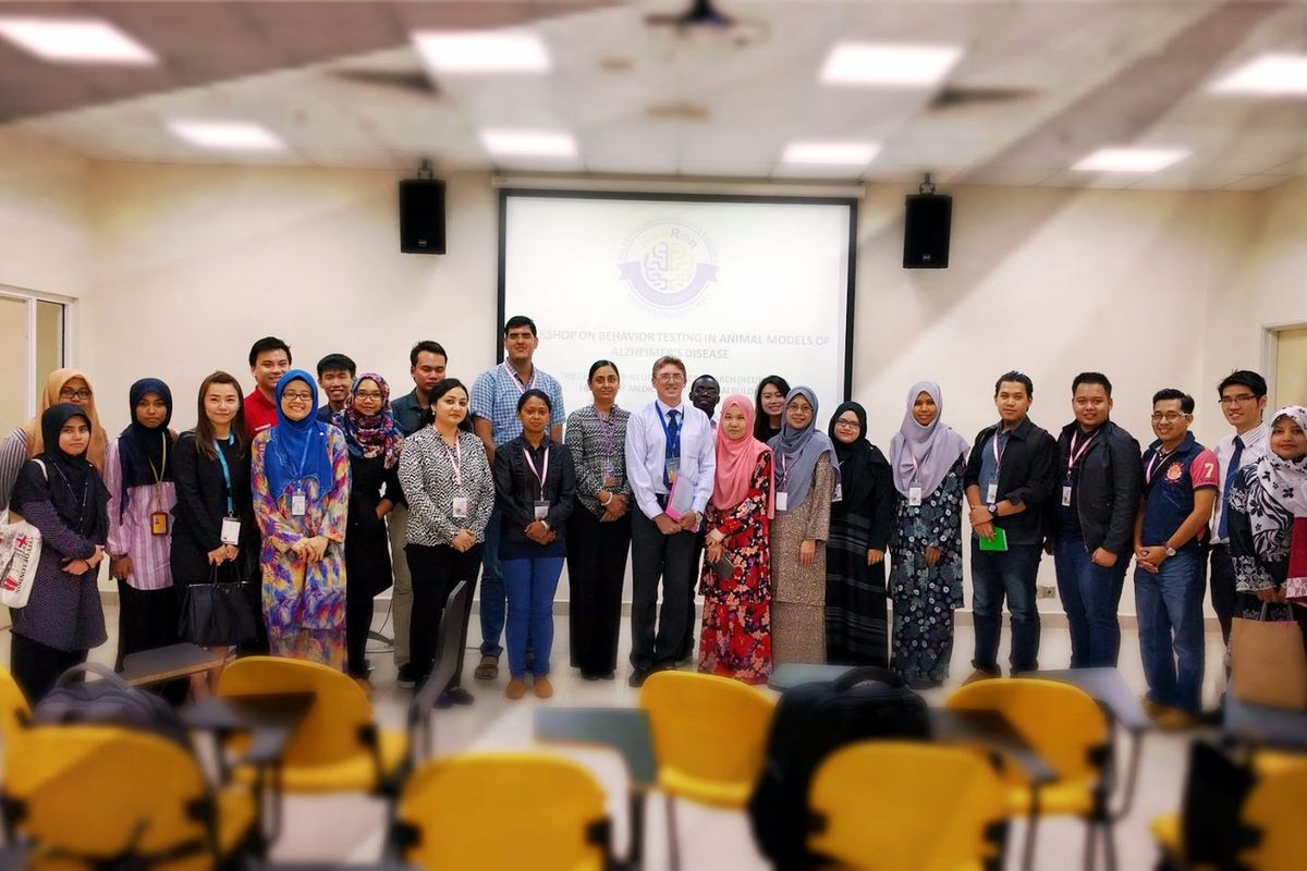 A large group of participants and organisers standing together for a group photo in a seminar room