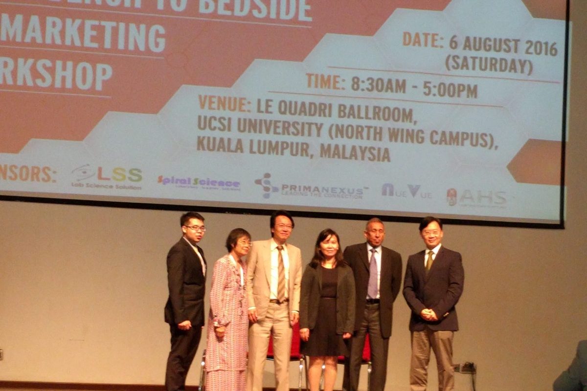 Six people standing in a row on stage under the workshop slide showing the date, venue and supporters