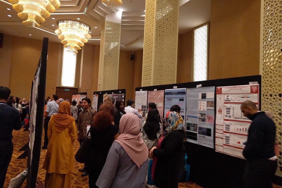 Delegates standing and reading research posters along a row of boards in the hotel hall