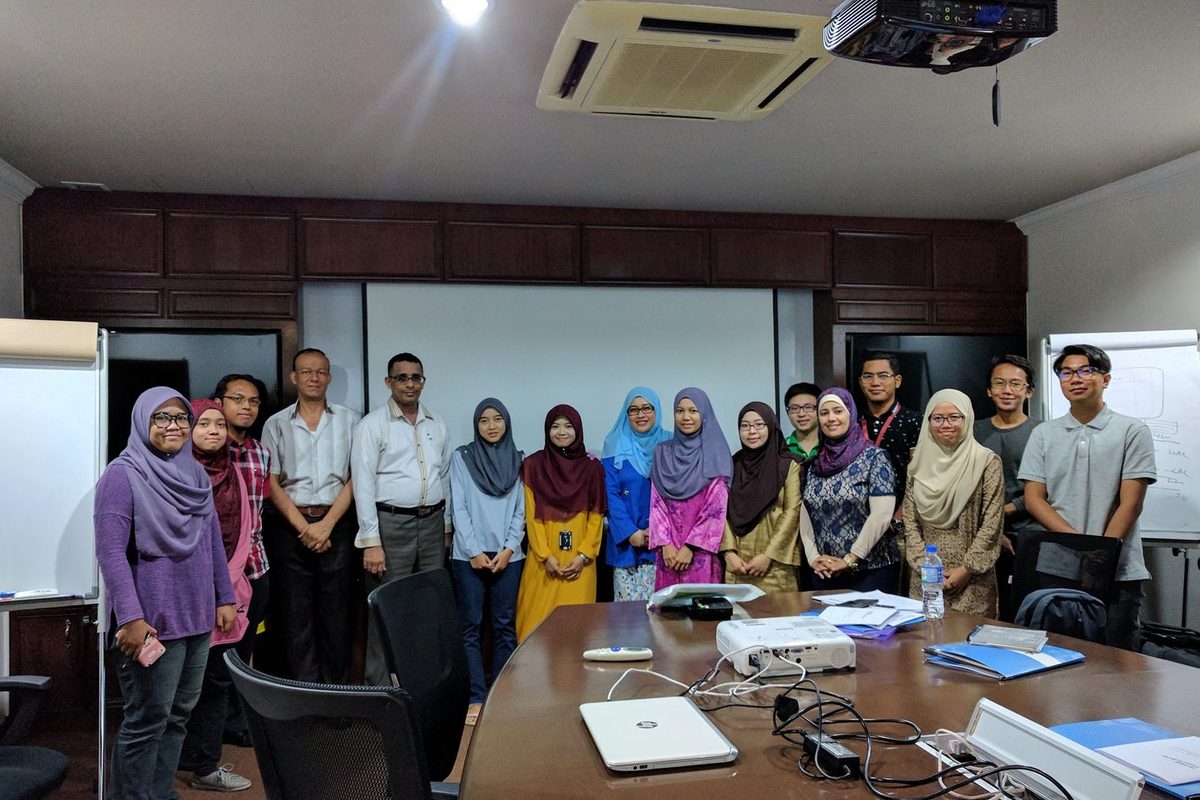 The workshop group standing together for a photo in a meeting room with a long table and a projector