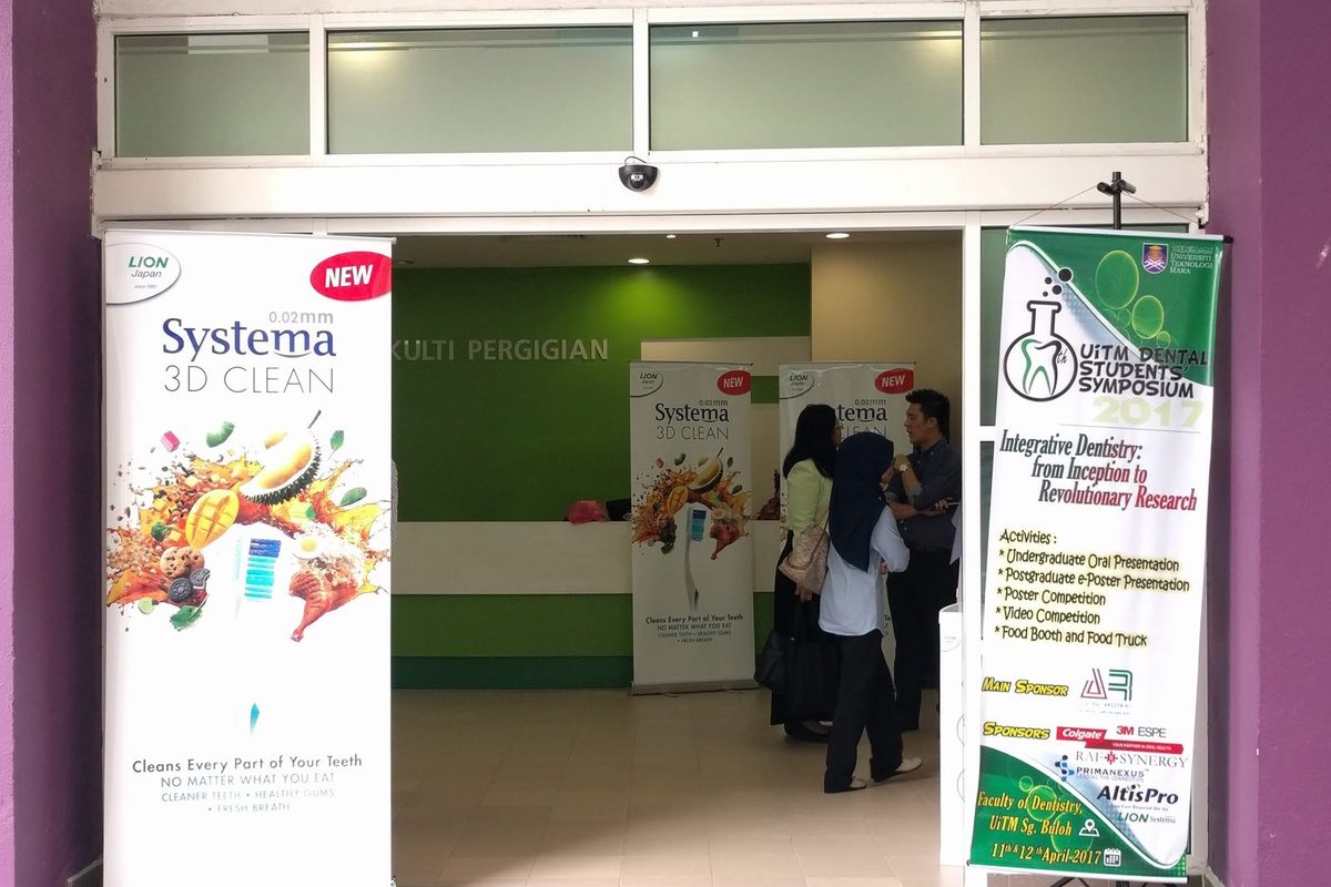 The Faculty of Dentistry entrance, with visitors inside and the symposium banner on a stand by the door