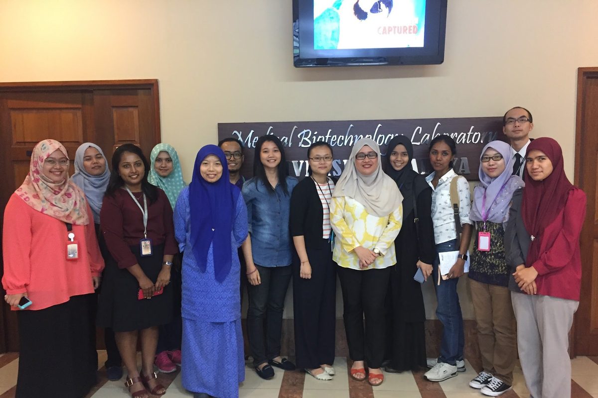 Group photo of the workshop participants standing in a row in front of the Medical Biotechnology Laboratory banner