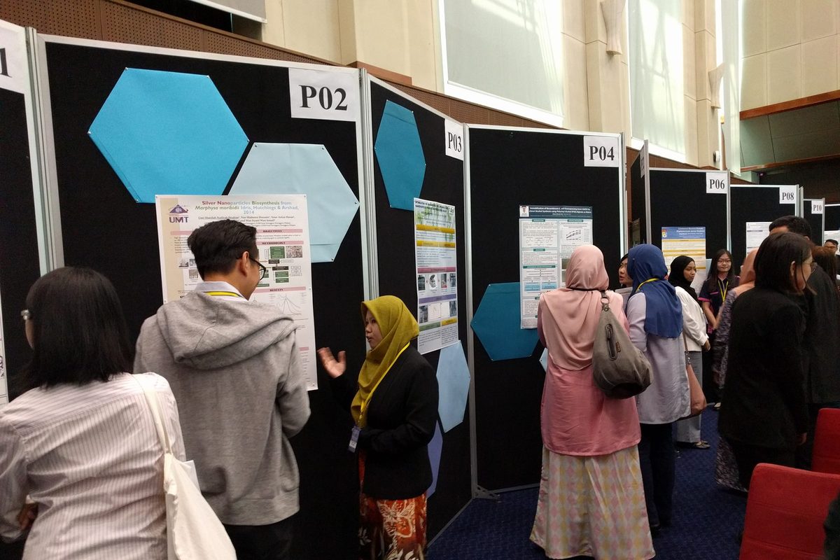 Visitors read research posters pinned to numbered display boards in the ballroom