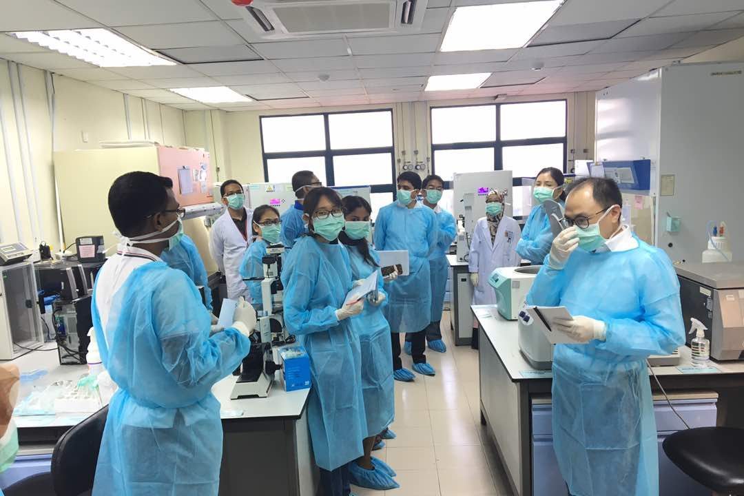 Workshop participants in blue gowns, masks and shoe covers in the tissue culture laboratory