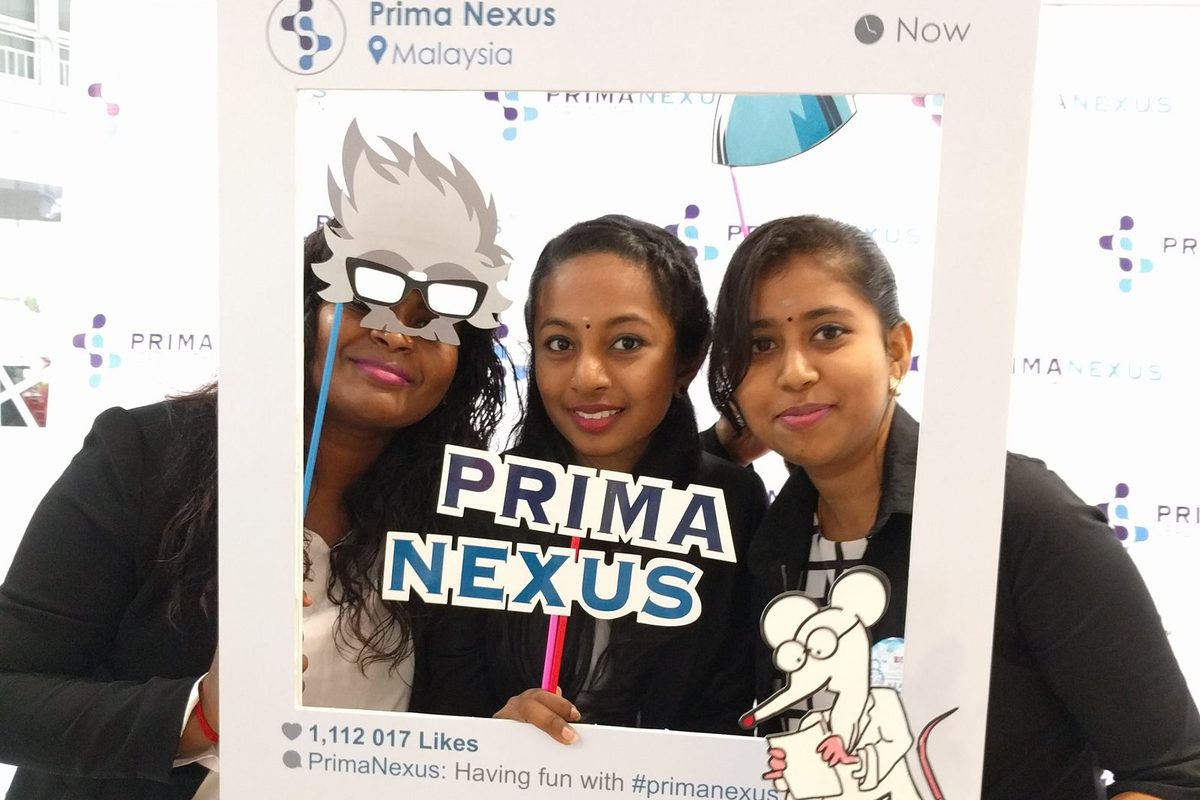 Three participants holding Prima Nexus props inside a large social media style photo frame