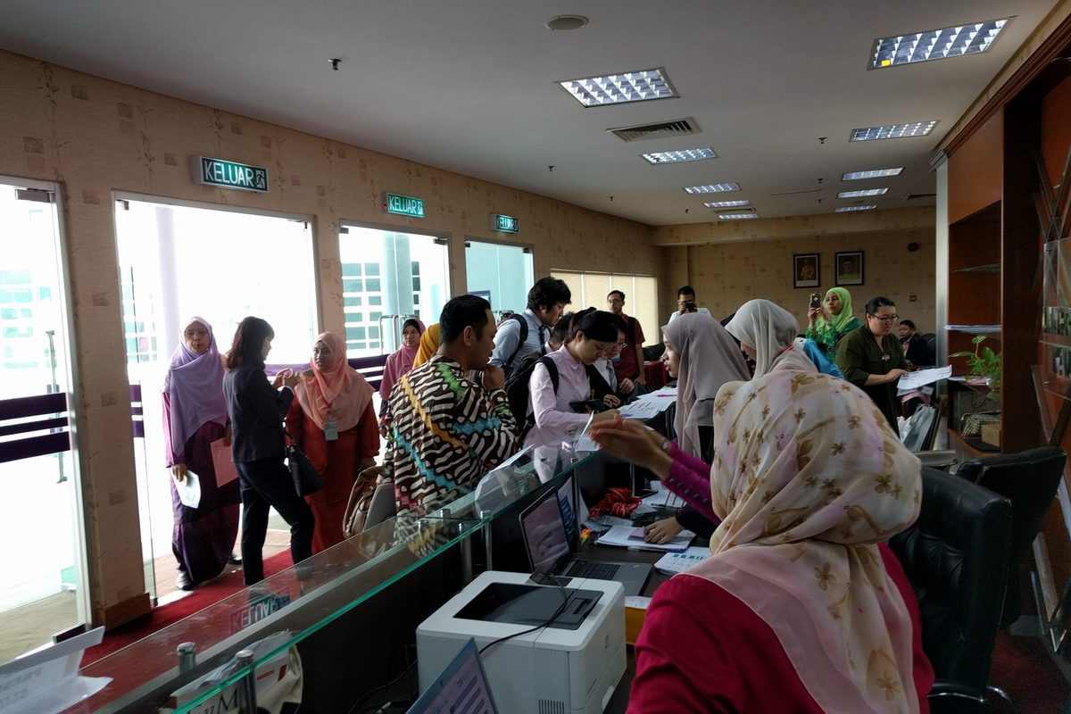 Delegates registering at a reception counter by the hall entrance