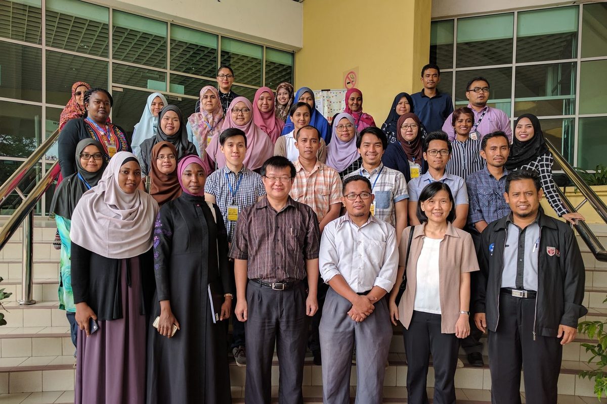 Workshop participants gathered for a group photo on an outdoor staircase at UPM