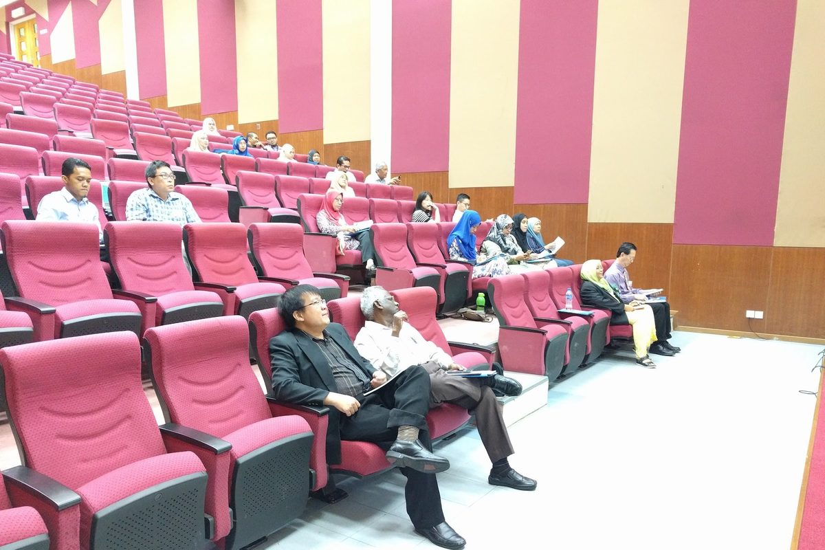 Members seated in the lecture hall’s rows of red seats