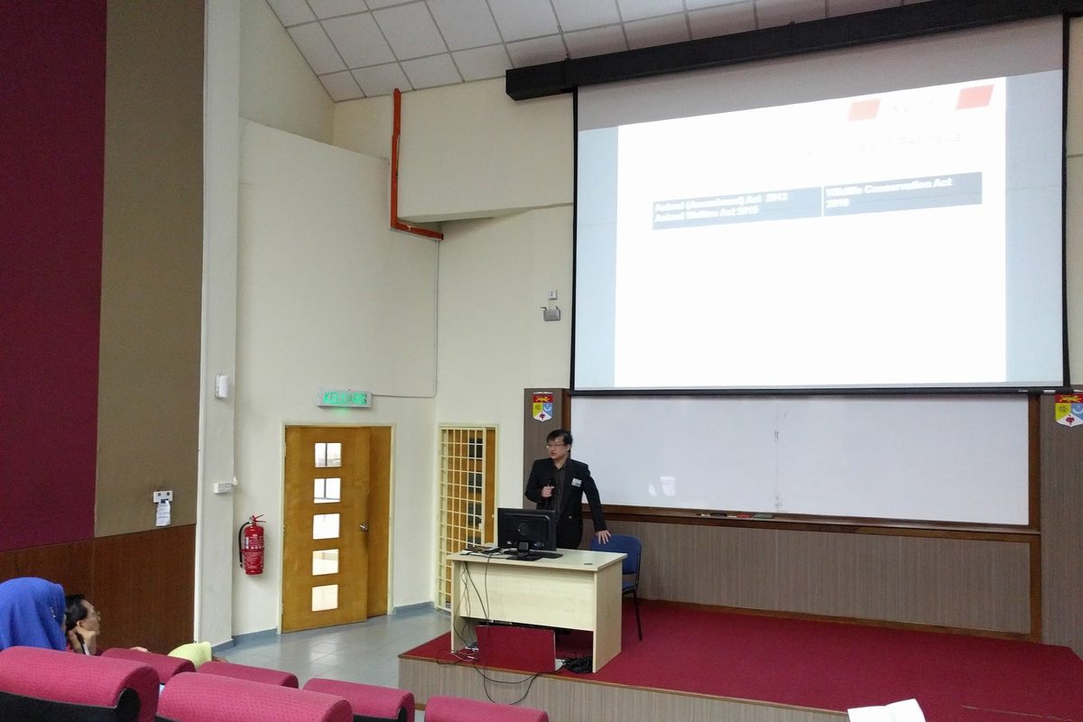 The lecture hall with a slide on the screen and members seated