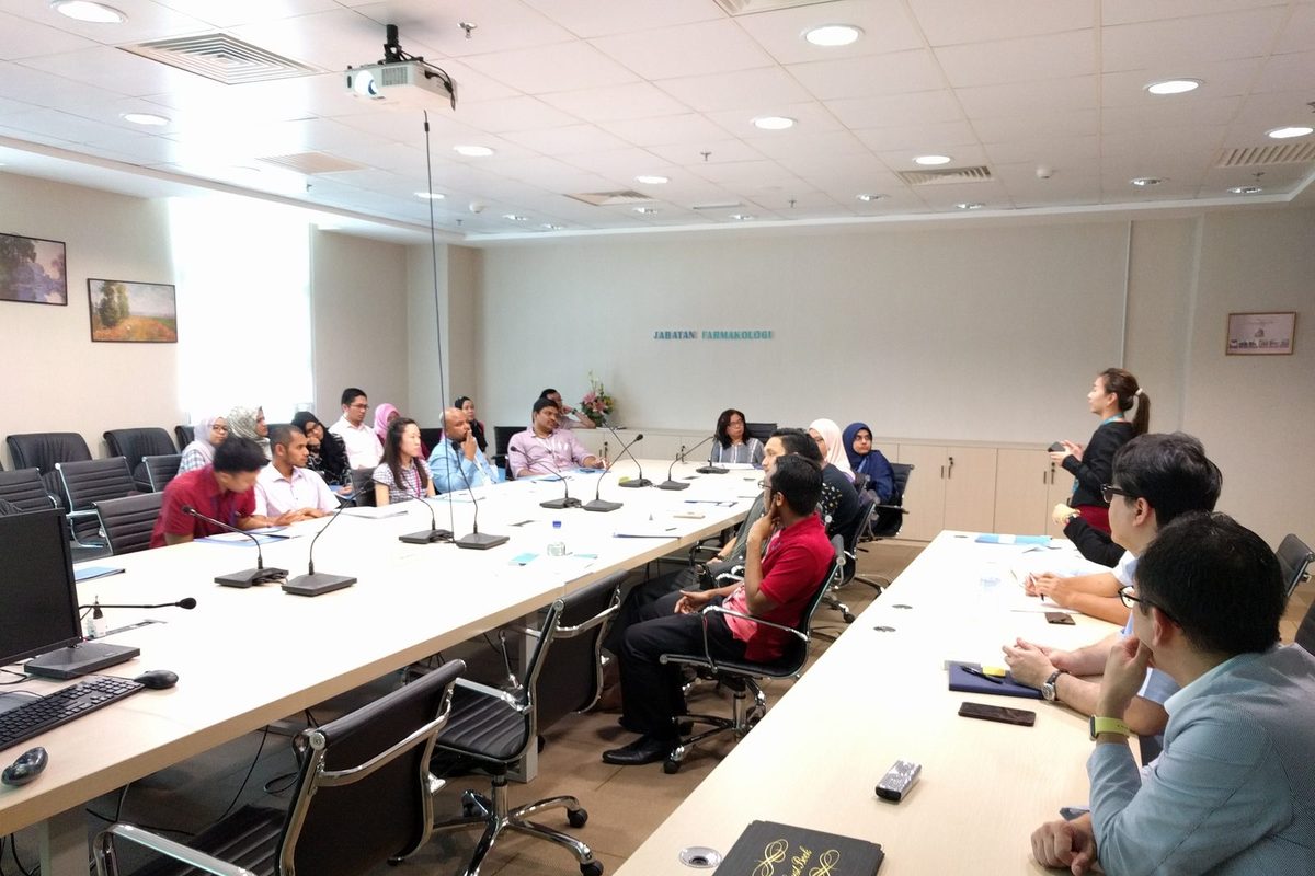 Researchers seated around long tables in the PPUKM seminar room, with a presenter standing at the front