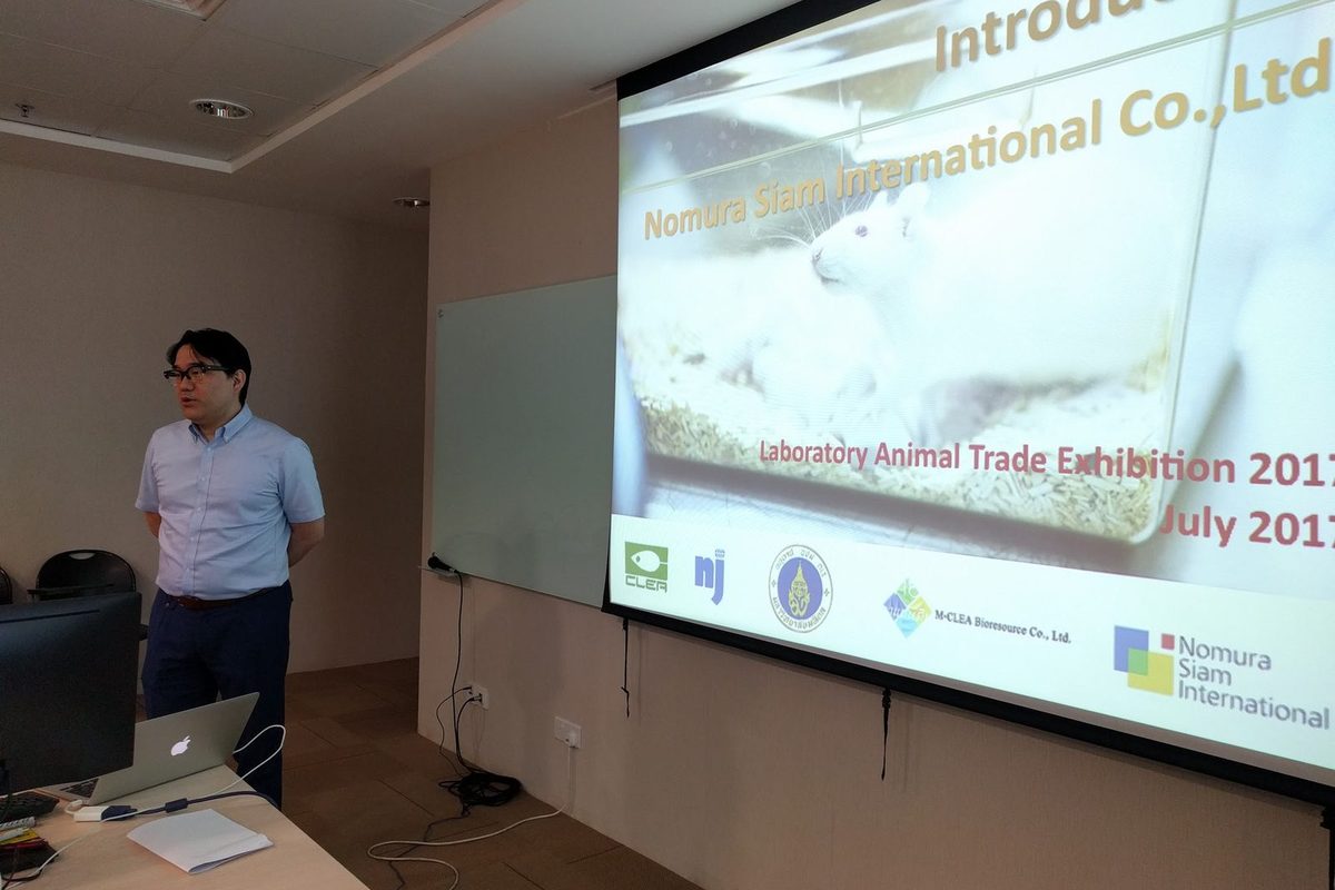 A presenter from the partner company stands beside a projected slide