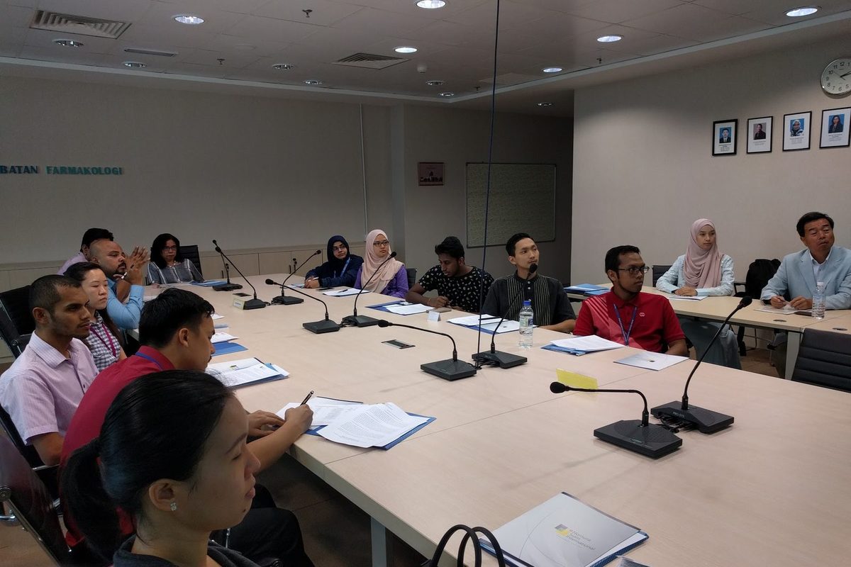 Participants seated along the conference table during the seminar, one taking notes