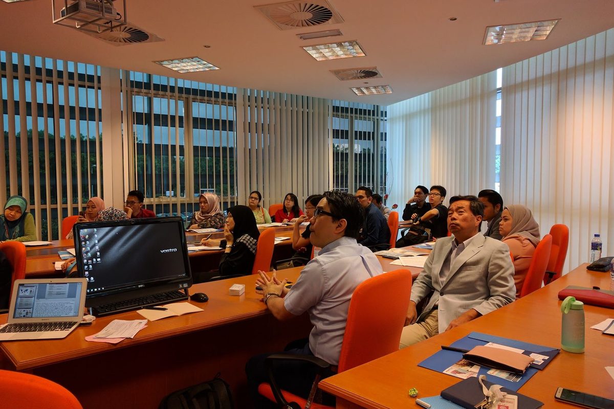 Participants around the meeting table following a talk, with a computer screen in front of them