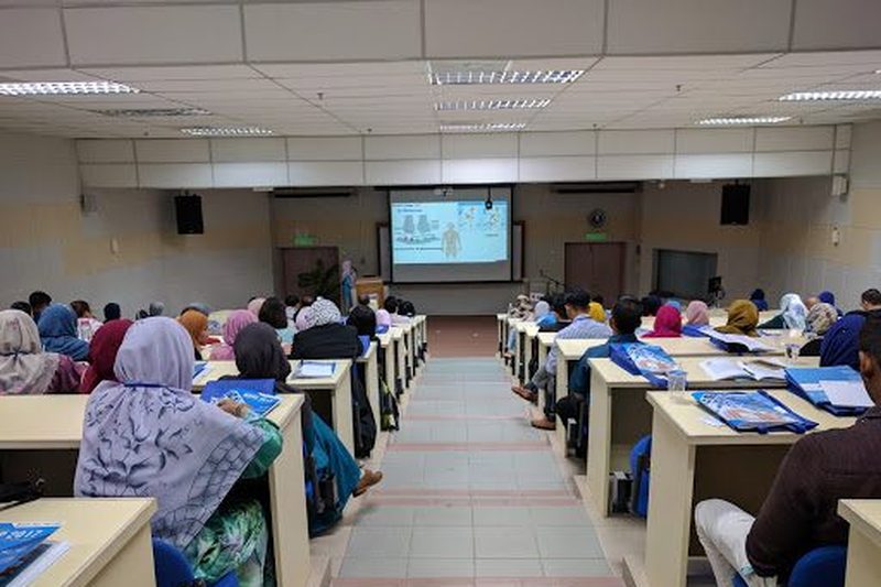 A full lecture hall of delegates facing a projected slide during a talk