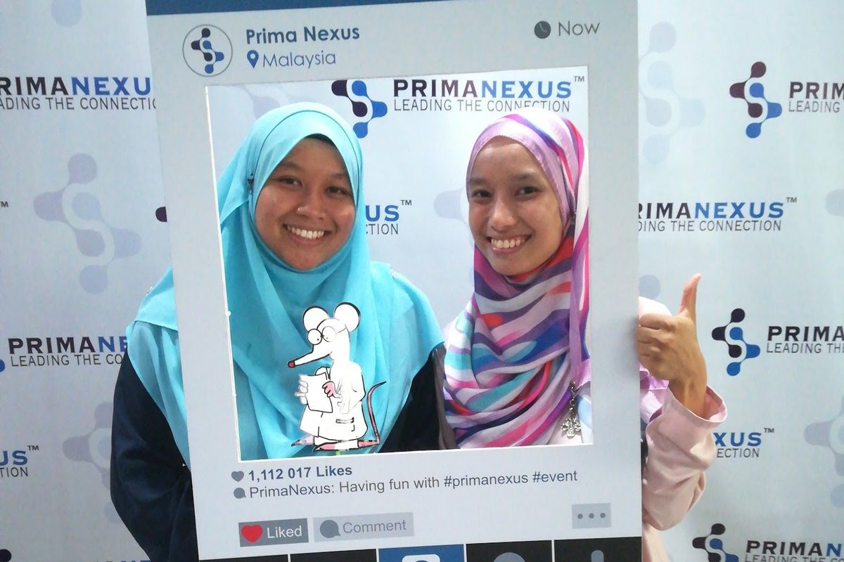 Two delegates pose with a photo frame at the Prima Nexus photo wall