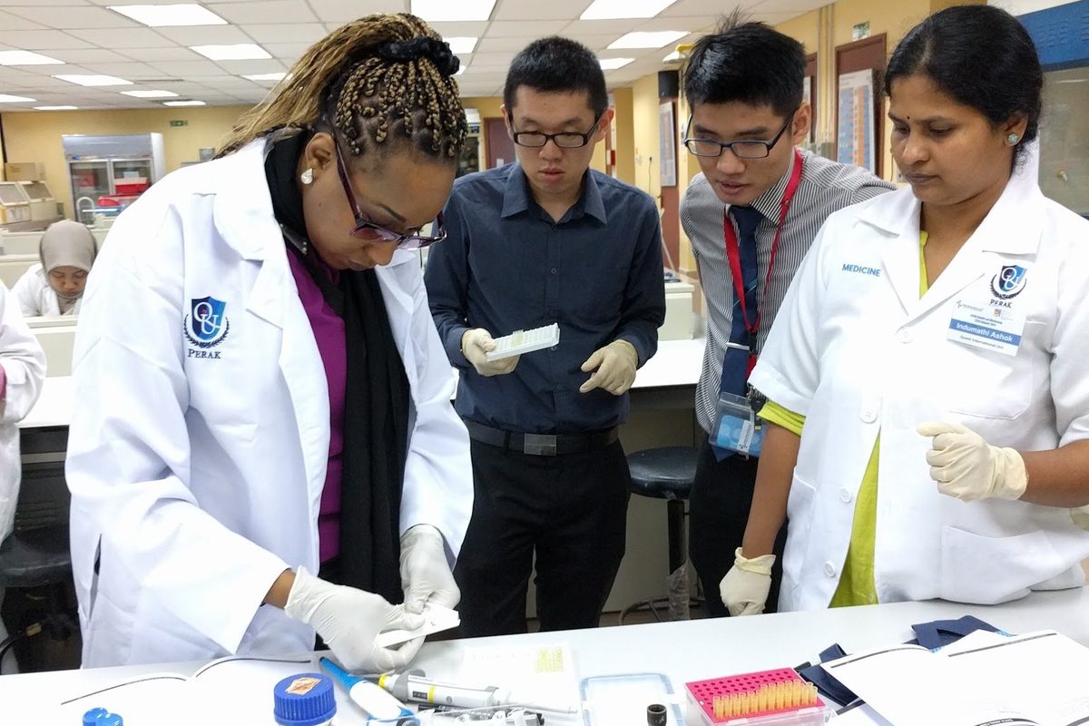 A trainer demonstrates a step at the laboratory bench while participants watch