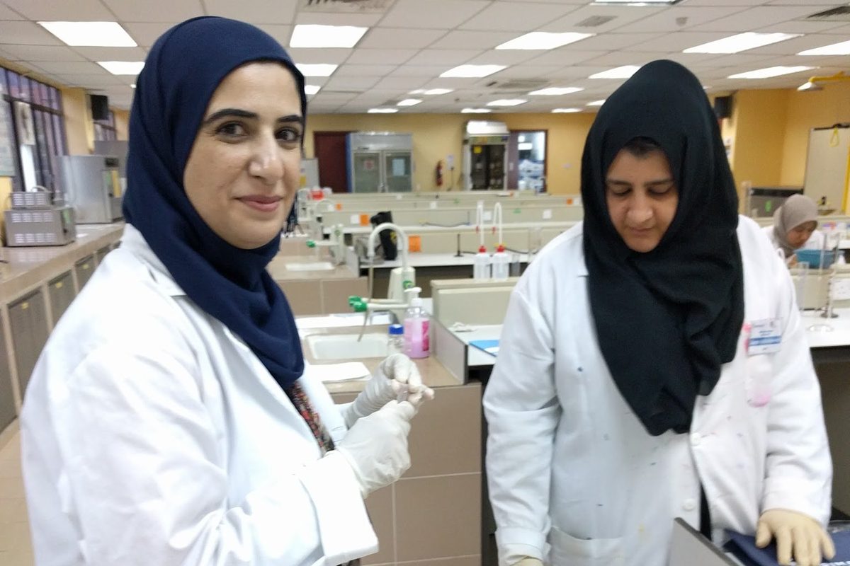 Two participants in lab coats at a laboratory bench
