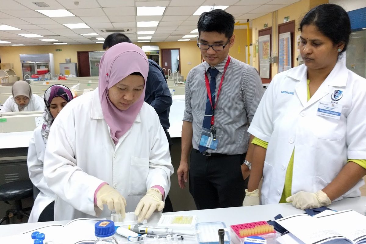 Participants in lab coats at the bench with the workshop materials