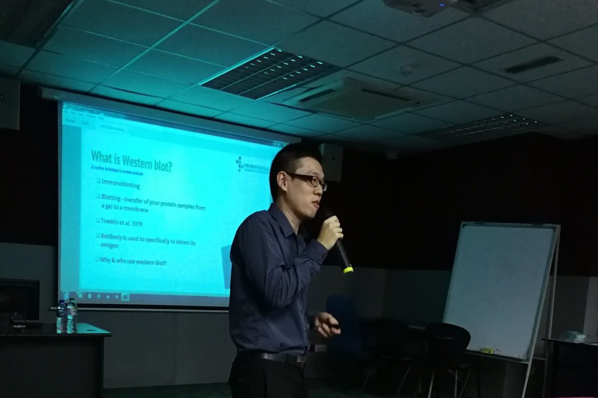 A speaker presents in a darkened lecture room