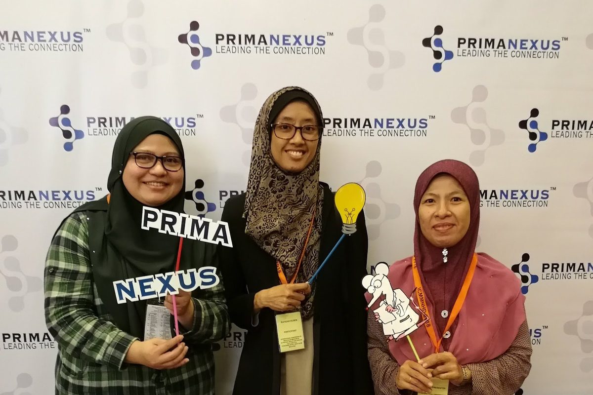 Three delegates holding photo props at the Prima Nexus photo wall