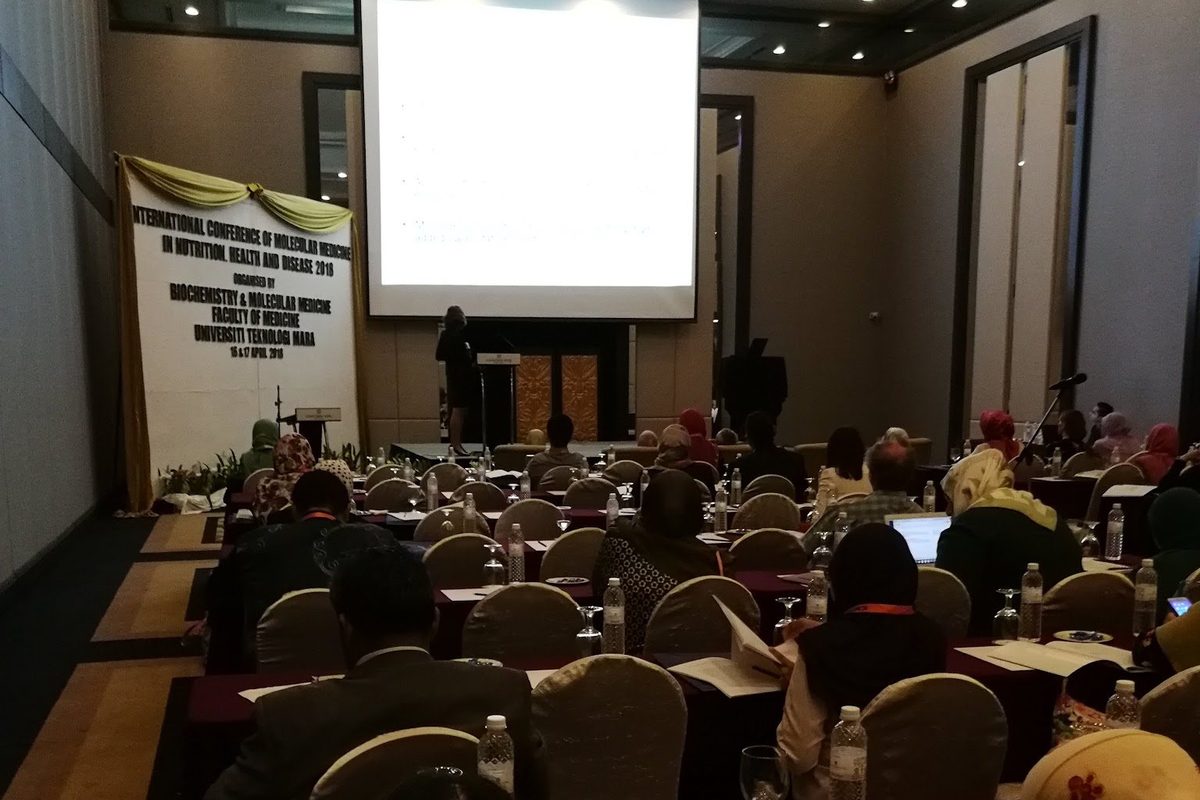 Delegates seated in the conference hall facing the screen
